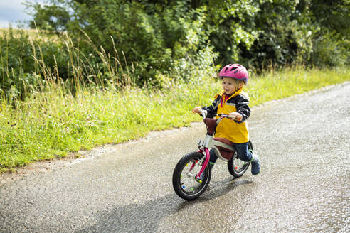 Toddler girl with pink cycling helmet on balance bicycle - BRF01485