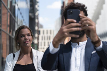 Businessman with smartphone and businesswoman in business district in the city - HPSF00046