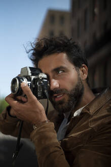 Portrait of man taking picture in the city with old-fashioned camera - HPSF00049