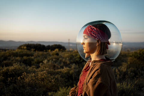 Frau mit einem Fischglas auf dem Kopf auf dem Lande, lizenzfreies Stockfoto