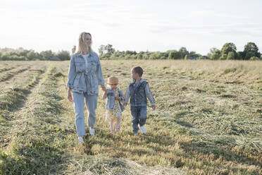 Lächelnde Mutter mit zwei Kindern auf einem Feld - EYAF01227