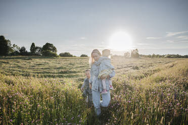 Lächelnde Mutter mit zwei Kindern auf einem Feld - EYAF01230