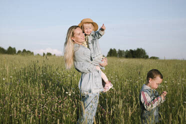 Lächelnde Mutter mit zwei Kindern auf einem Feld - EYAF01231