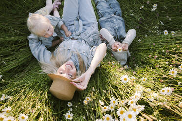 Smiling mother with daughter and son lying on flower field - EYAF01235