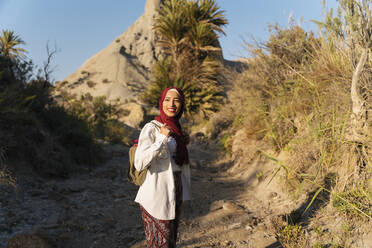 Lächelnde junge Touristin mit Hijab auf einer Wandertour - MPPF00960