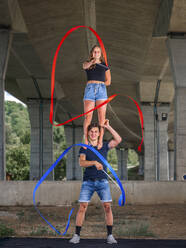 Young couple doing acrobatics with fitness band - STSF02582