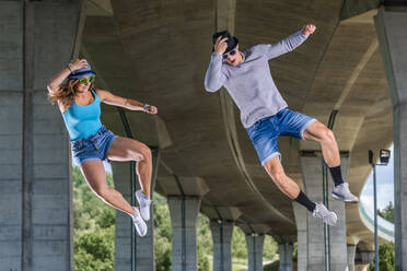 Young couple doing acrobatics under bridge - STSF02588