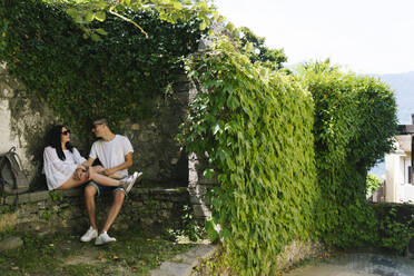 Junges verliebtes Paar auf einer Bank sitzend, Bellagio, Italien - MCVF00550