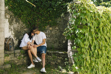 Young couple in love sitting on bench, Bellagio, Italy - MCVF00551