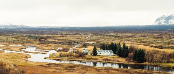 Von oben malerischer Blick auf ein Tal mit Fluss und Landhaus zwischen riesigen Feldern in Island - ADSF08966