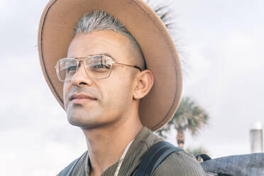 Young man expressing joy and posing for a photo in glasses and a brown hat. Portrait - ADSF09093