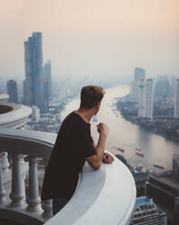 Man on balcony viewing Bangkok in haze - ADSF09120