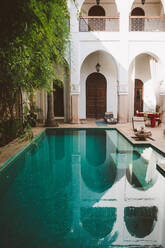 Friedliches klares Wasser des Pools auf der Terrasse eines exotischen Resorts mit orientalischer Architektur im Sonnenlicht, Marokko - ADSF09124
