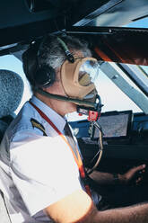 Pilot mit Maske, der das Flugzeug während des Fluges bedient - ADSF09167