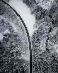 Luftaufnahme einer leeren Asphaltstraße, die sich durch den schneebedeckten Wald im Achtal zieht - MALF00052