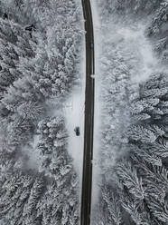 Luftaufnahme der Asphaltstraße, die durch den verschneiten Wald im Achtal führt - MALF00055