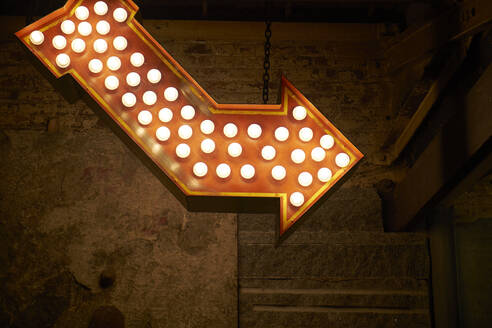 Low Winkel der beleuchteten roten Pfeil mit glühenden Glühbirnen hängen auf schäbigen Wand in der Nacht Stadt Straße - ADSF09213