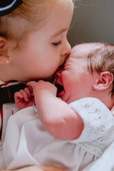 Closeup of crop caring little girl hugging and kissing crying newborn baby sibling - ADSF09257