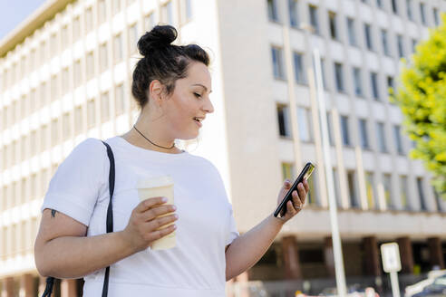 Kurvige junge Frau, die in der Stadt ein Mobiltelefon benutzt - GIOF08645