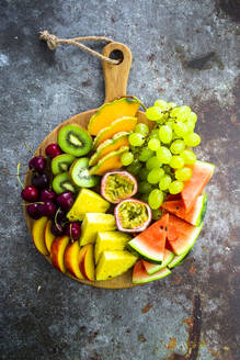 Obstsalat mit Wassermelone, Kiwi, Passionsfrucht, Traube, Kirsche, Pfirsich und Melone auf Schneidebrett - GIOF08676