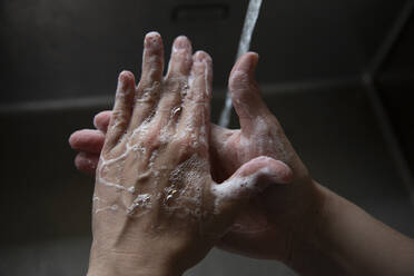 Nahaufnahme von jemandem, der sich die Hände mit Seife im Waschbecken schrubbt - CAVF87982