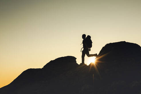 Mann Silhouette über einen Felsen bei Sonnenuntergang - CAVF88064