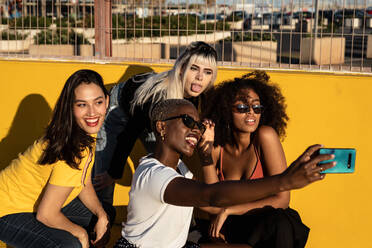 Fröhliche junge verschiedene weibliche Freunde nehmen Selfie auf Smartphone in der Straße - ADSF09376