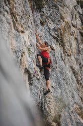 Entschlossene Frau klettert auf felsigen Berg - DMGF00111