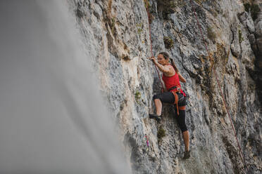 Confident female rock climber climbing mountain - DMGF00112