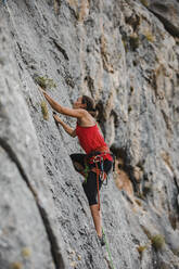 Determined female climber climbing rocky mountain - DMGF00118