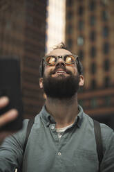 Glücklicher Mann mit Sonnenbrille bei einem Selfie in der Stadt - HPSF00052