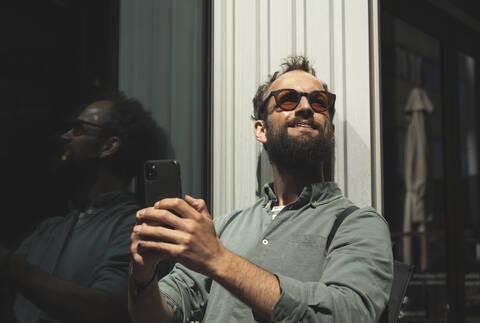 Man posing while taking selfie through smartphone in city stock photo
