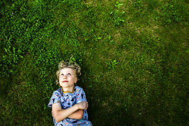 Smiling boy lying down on grass in park - IHF00377