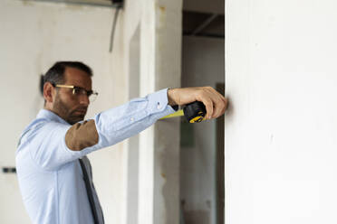 Architekt mit Maßband in einem im Bau befindlichen Haus - VABF03290