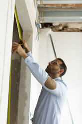 Architect using tape measure in a house under construction - VABF03293