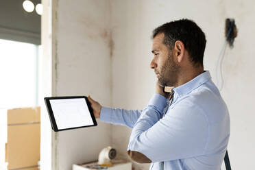 Architekt mit Tablet am Telefon in einem im Bau befindlichen Haus - VABF03297