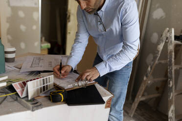 Architect at work with construction plan and colour swatch - VABF03310