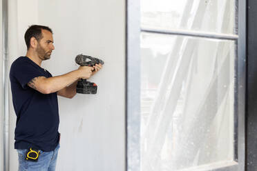 Construction worker using drill at a wall - VABF03325