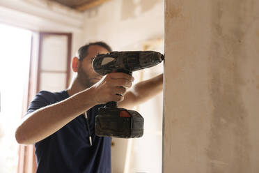 Construction worker using drill at a wall - VABF03329