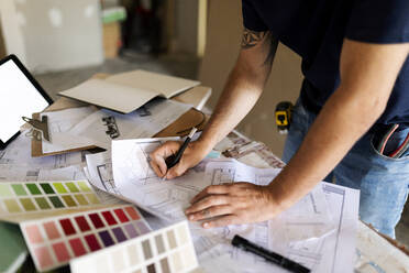 Man working on construction plan and colour swatch - VABF03347