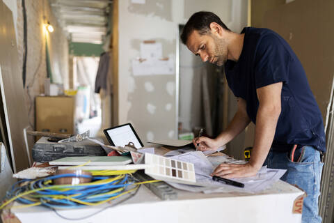 Man working on construction plan and colour swatch stock photo