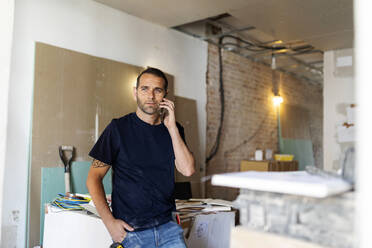 Mann am Telefon in einem im Bau befindlichen Haus - VABF03354