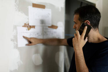 Mann am Telefon in einem im Bau befindlichen Haus - VABF03355