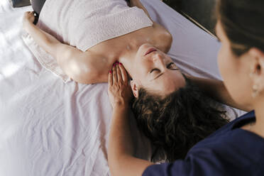 Therapist massaging female customer's neck relaxing on table in spa - EBBF00531