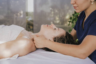 Close-up of female therapist massaging customer's neck on table in health spa - EBBF00533