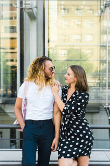 Stylish couple looking at each other while leaning on railing in city - JMPF00274