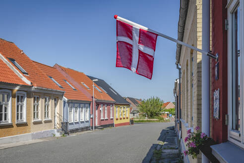 Dänemark, Region Süddänemark, Marstal, dänische Flagge hängt über leerer Stadtstraße - KEBF01568