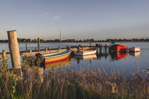 Denmark, Region of Southern Denmark, Ommel, Motorboats moored to coastal jetty at dusk - KEBF01607