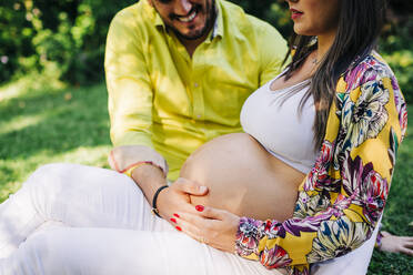Ehemann berührt Bauch der schwangeren Frau im Park - DCRF00577