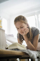 Girl reading a book at home - DKOF00002